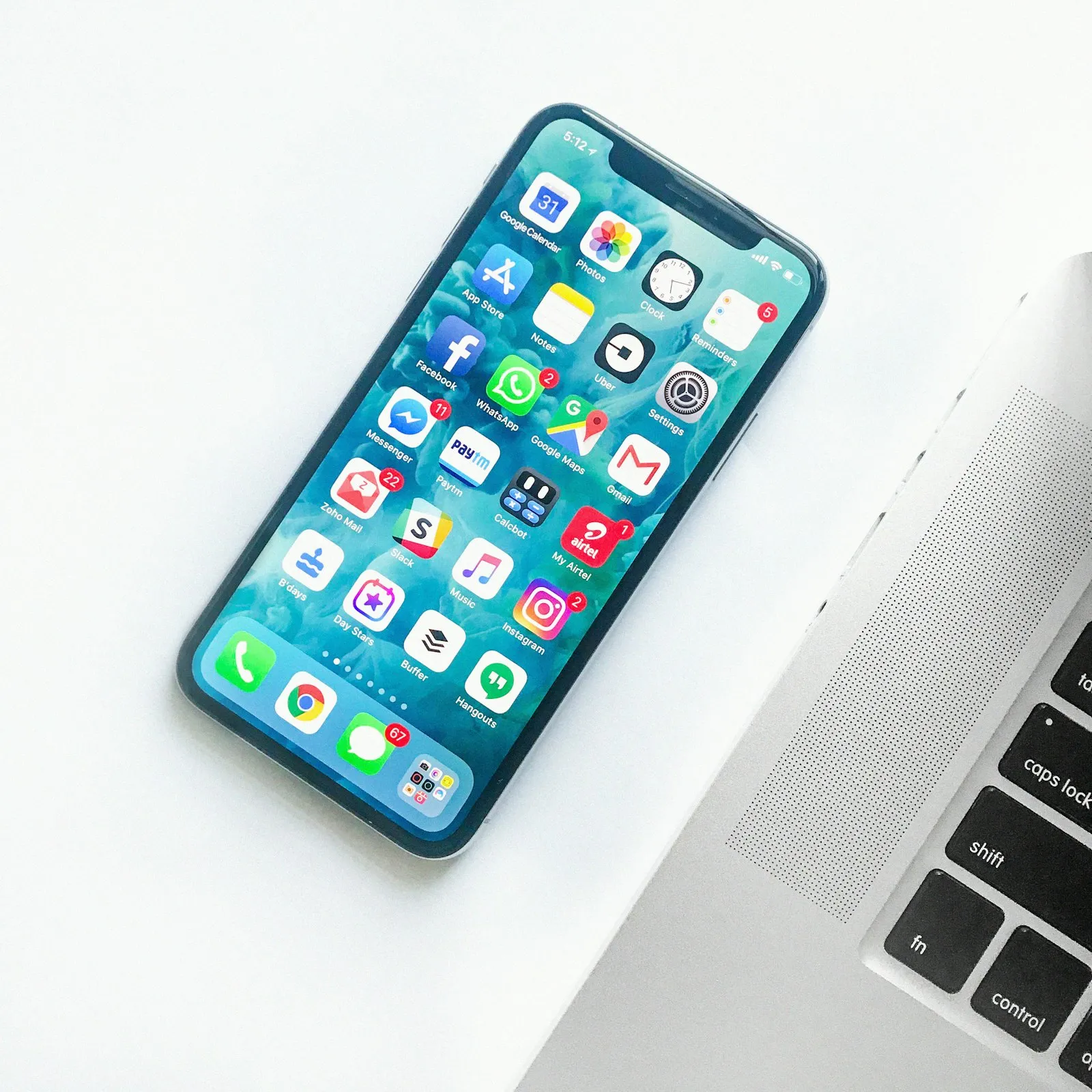 Smartphone menampilkan antarmuka aplikasi di samping laptop